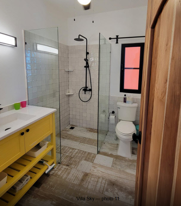 Modern bathroom with yellow vanity, tiled shower, and wooden floor