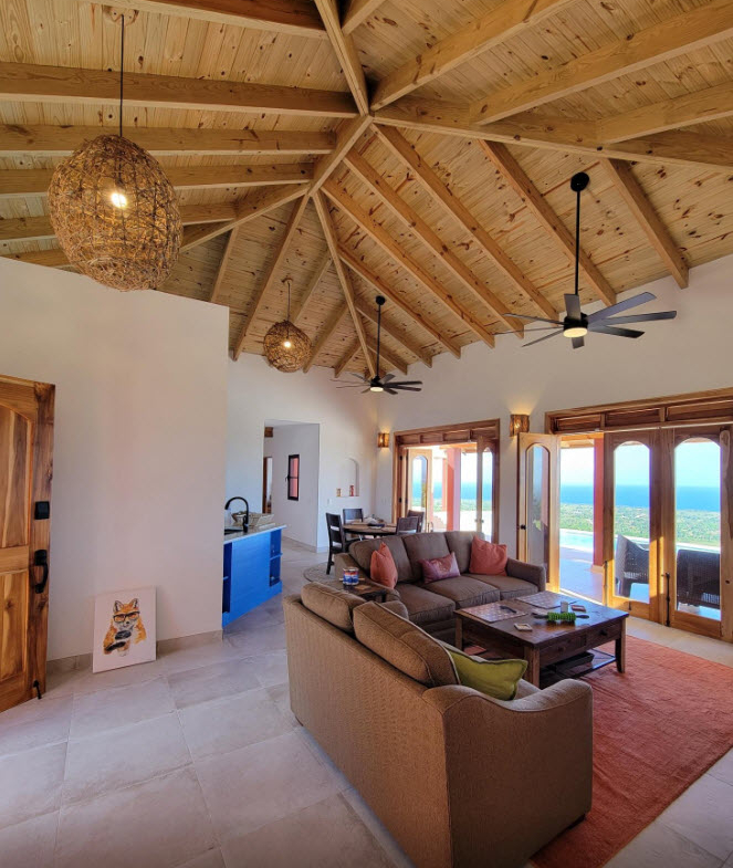 Spacious living room with vaulted wood ceiling, sofas, and ocean view