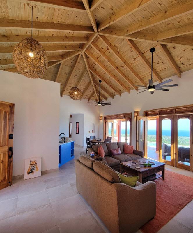 Spacious living room with vaulted wood ceiling, sofas, and ocean view