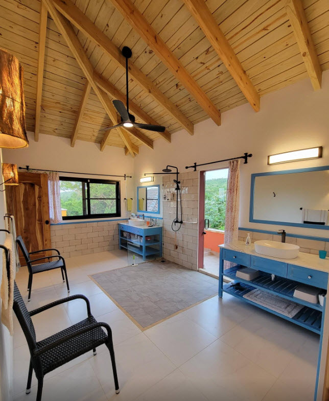 Spacious, modern bathroom with double vanities, walk-in shower, and balcony access