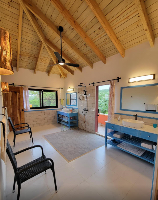 Spacious, modern bathroom with double vanities, walk-in shower, and balcony access