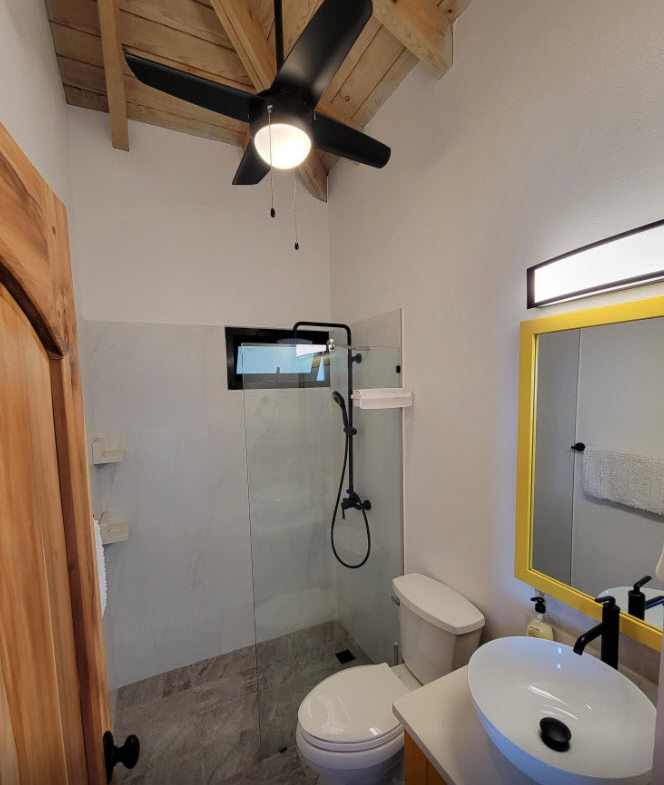 Modern bathroom with glass shower, white toilet, and yellow-framed mirror