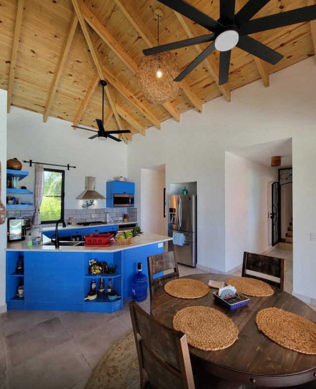 Bright, modern kitchen with vibrant blue island and wooden ceiling