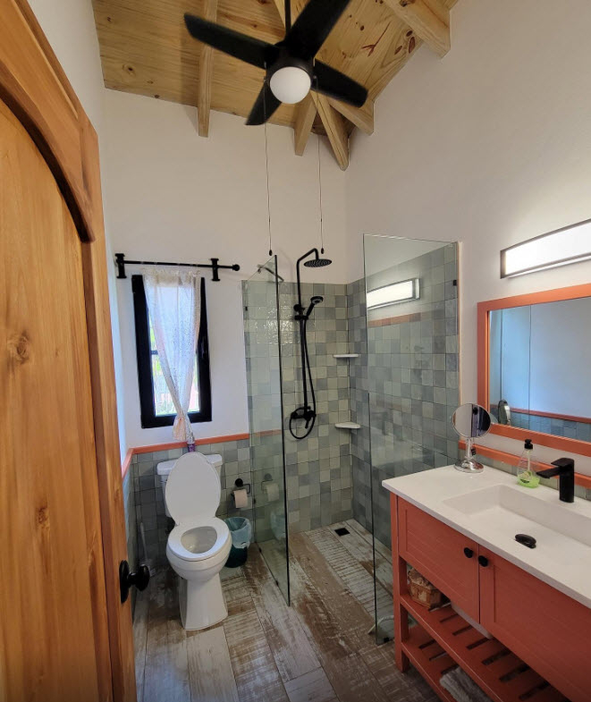 Modern bathroom with walk-in shower, wood accents, and orange vanity.