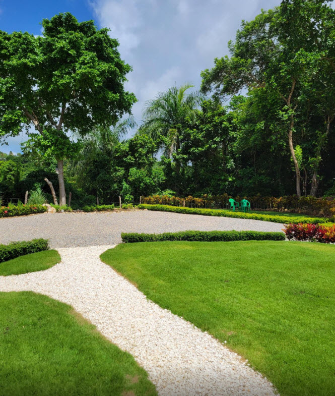 Lush green lawn and white gravel path leading to a tropical villa