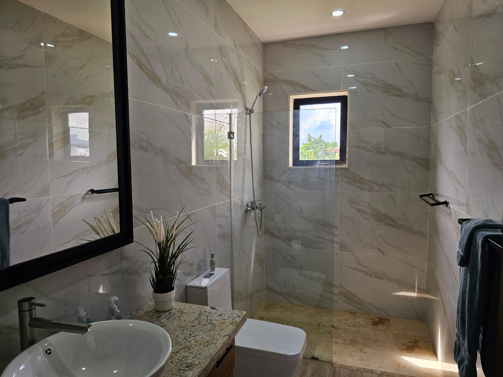 Modern bathroom with marble tiles, walk-in shower, and granite vanity.