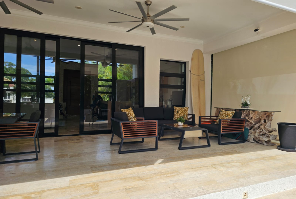 Modern patio furniture and surfboard on a covered terrace with sliding glass doors