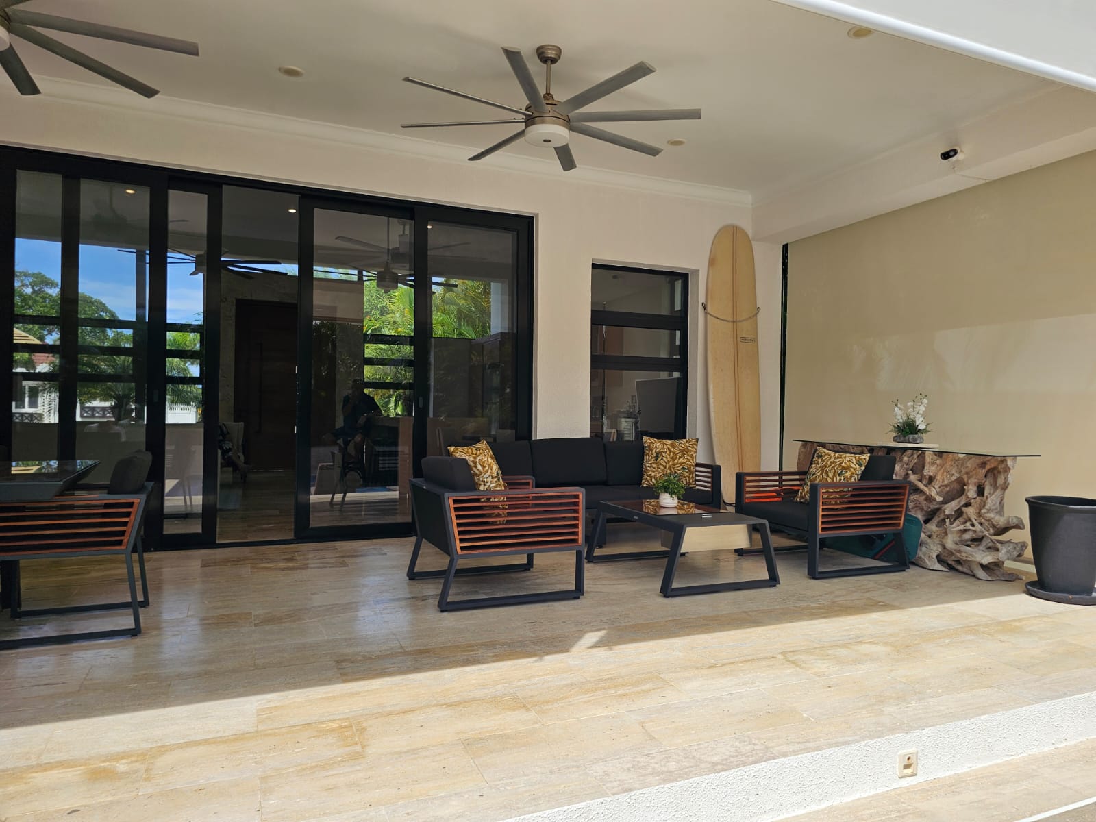 Modern patio furniture and surfboard on a covered terrace with sliding glass doors