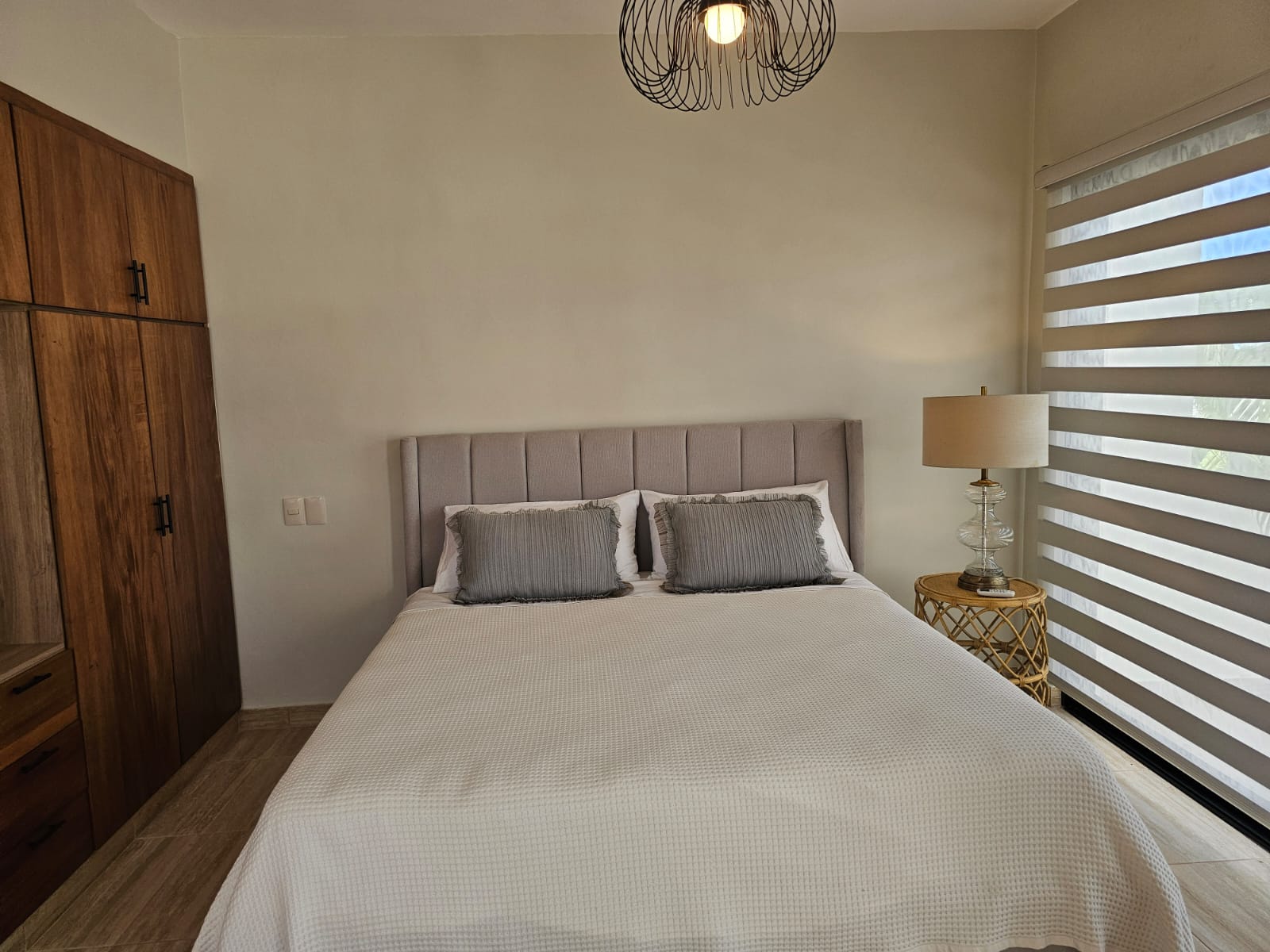 Modern bedroom with a queen bed, nightstand, and wood wardrobe