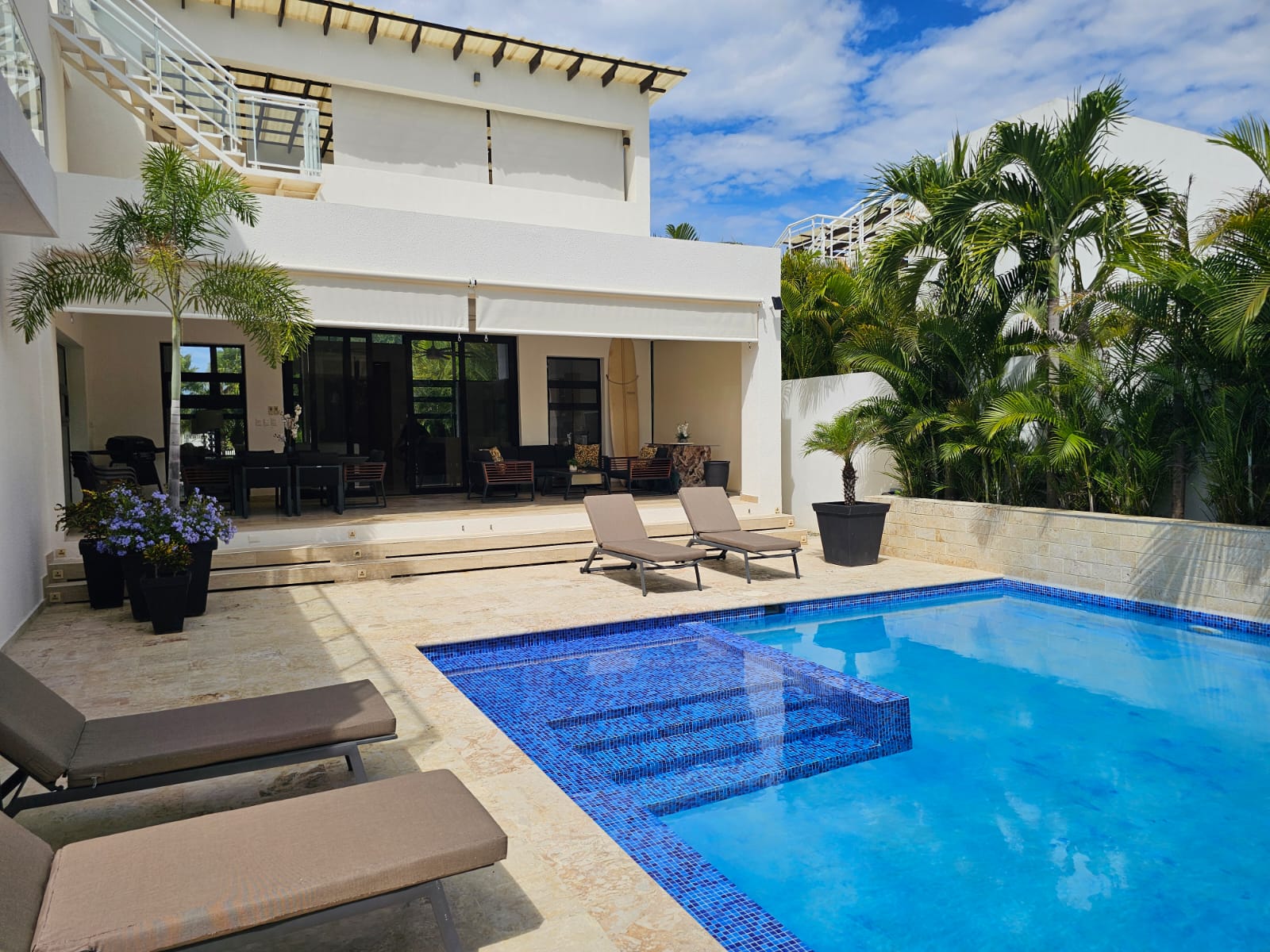 Modern villa with a blue tiled swimming pool and lounge chairs.