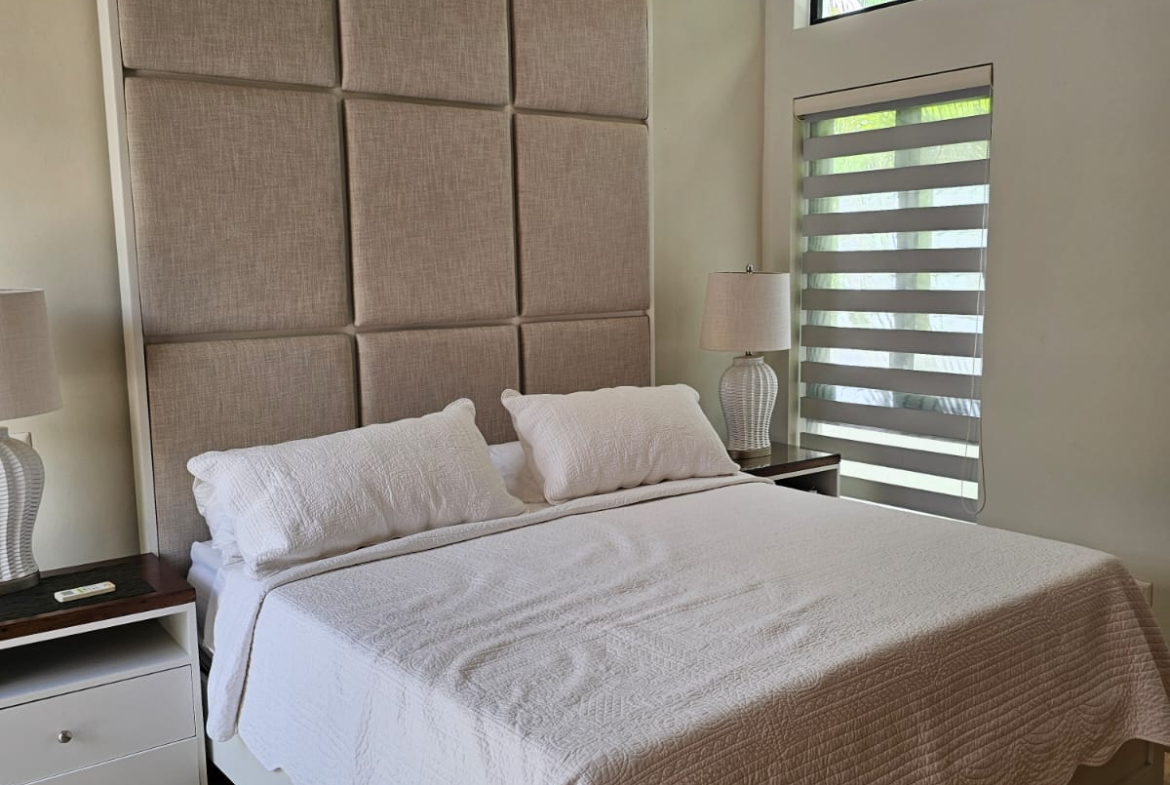 Modern bedroom with a large upholstered headboard and white bedding