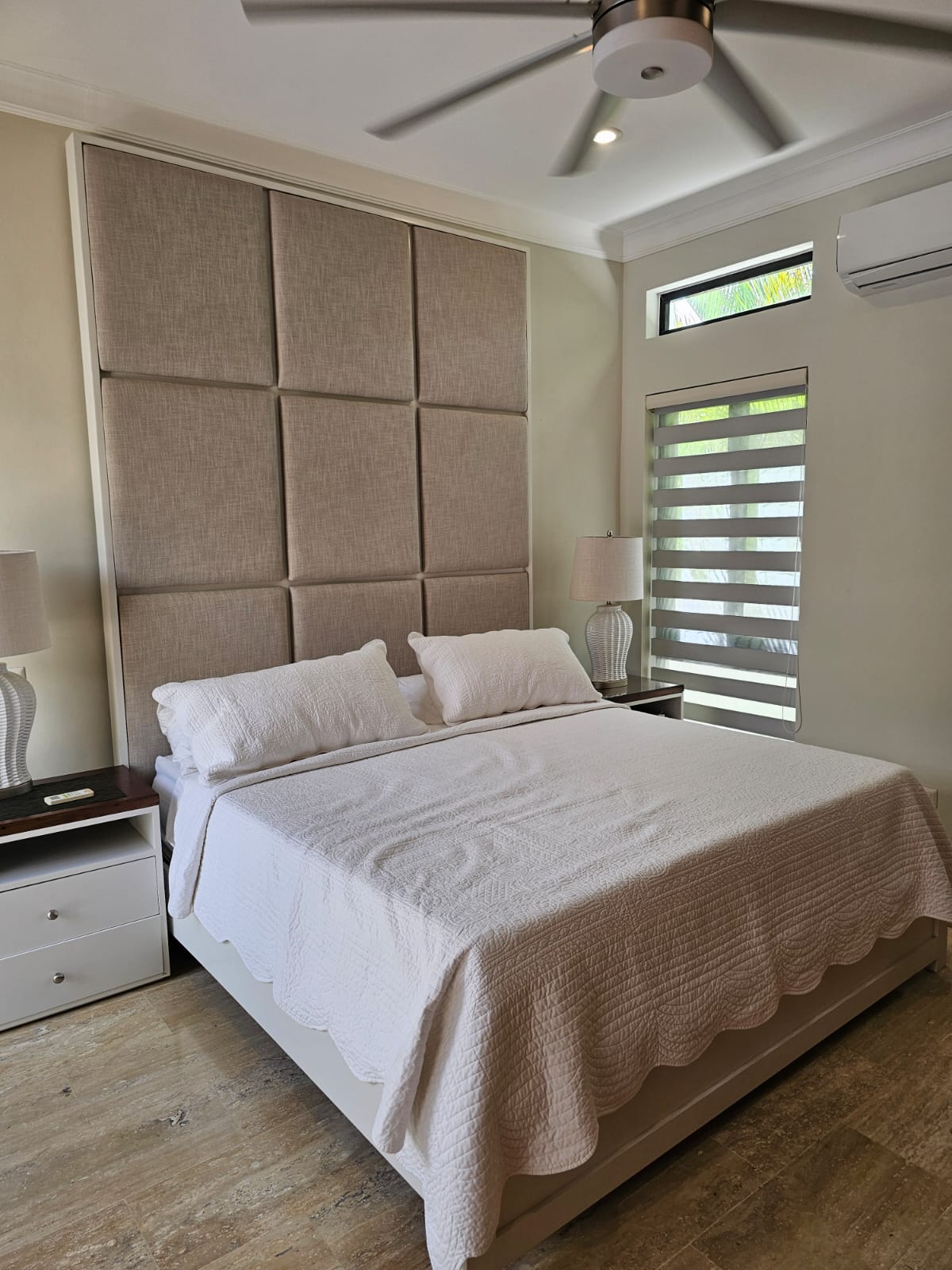 Modern bedroom with a large upholstered headboard and white bedding