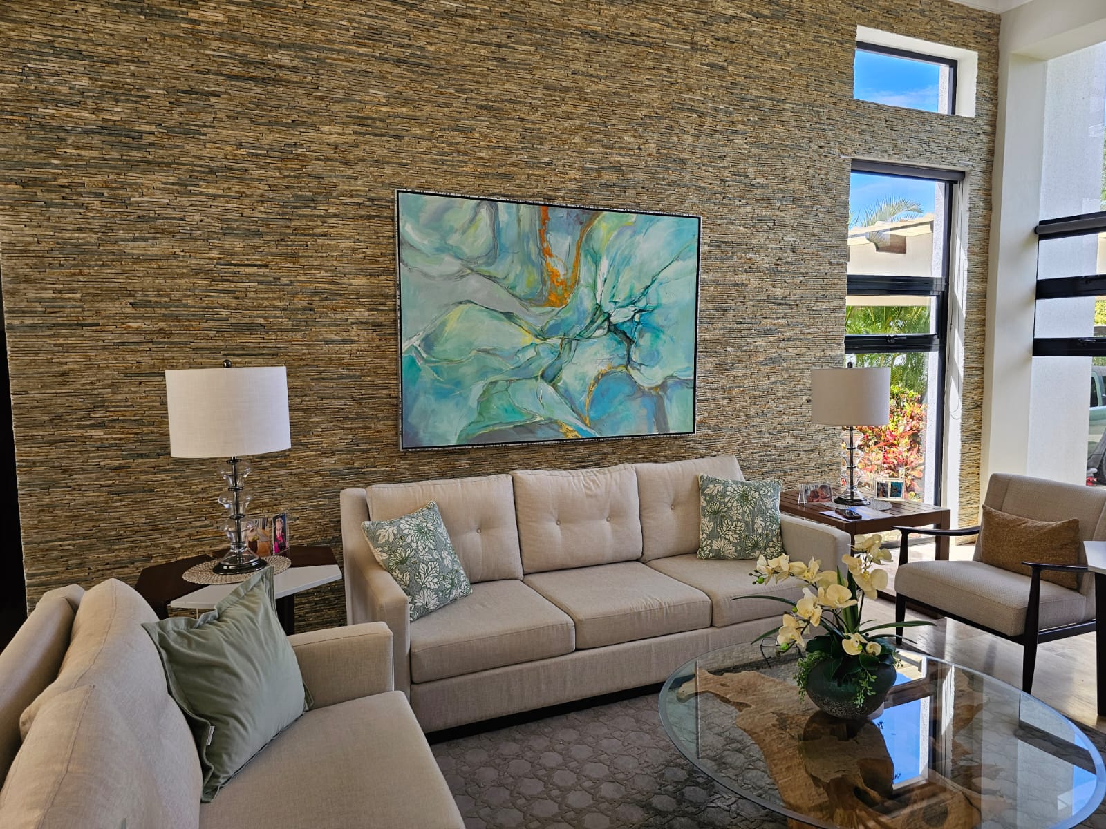 Modern living room with textured stone wall, abstract art, and comfortable seating.