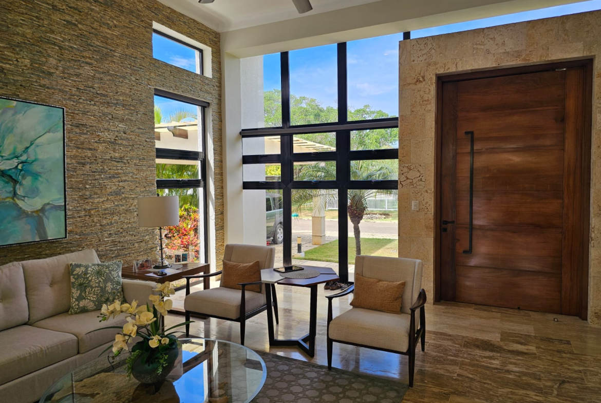 Modern living room with large windows, stone accent wall, and tropical view.