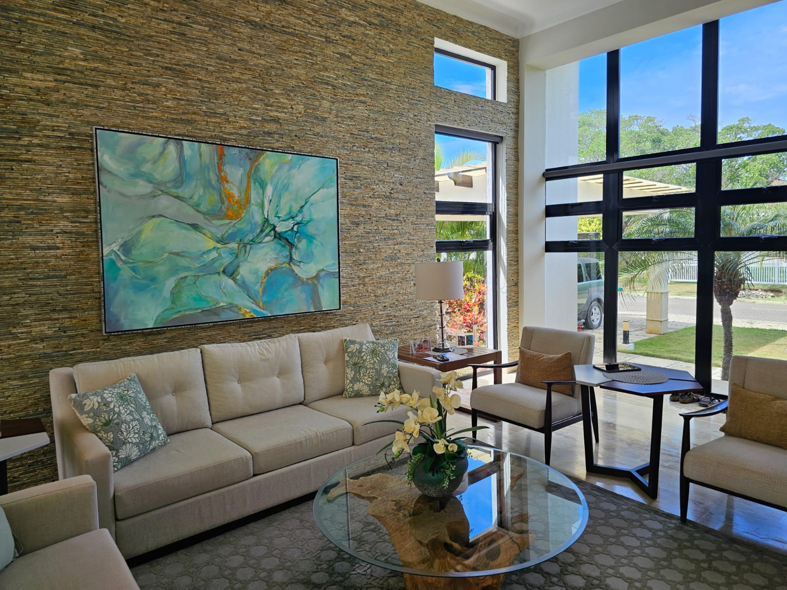 Modern living room with abstract art, stone accent wall, and large windows