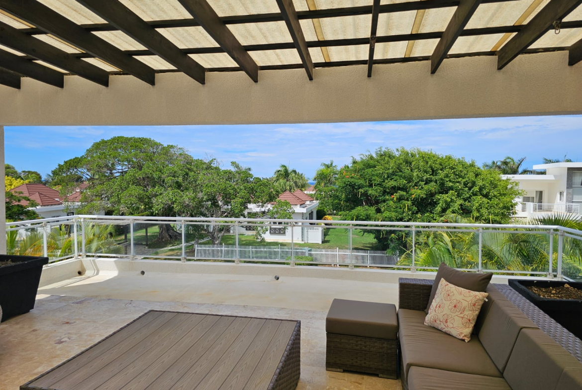 Spacious balcony with outdoor furniture overlooking lush greenery and the ocean