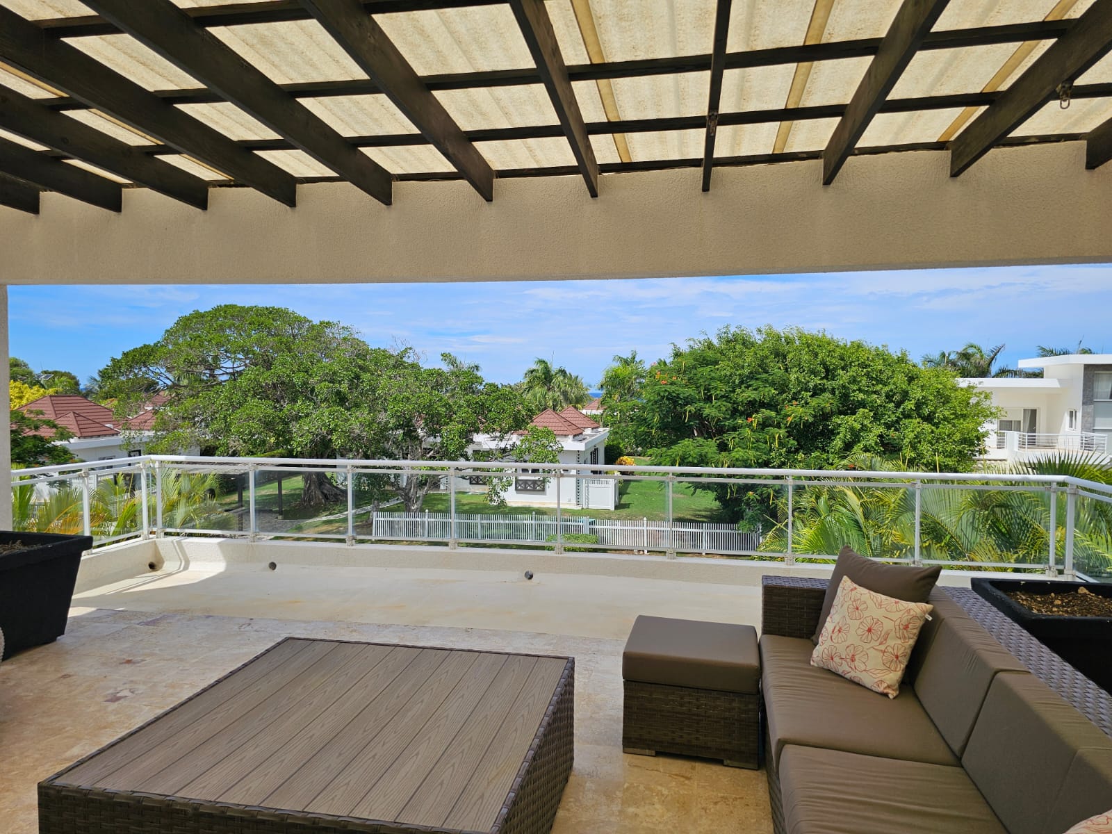Spacious balcony with outdoor furniture overlooking lush greenery and the ocean