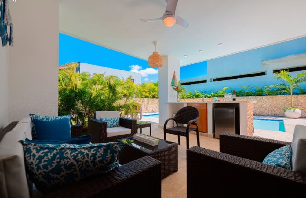 Luxurious outdoor patio with seating, a small pool, and tropical greenery