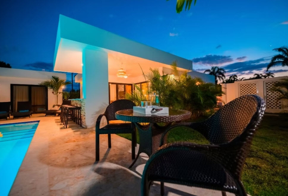 Luxury villa patio with pool at dusk, featuring table and chairs