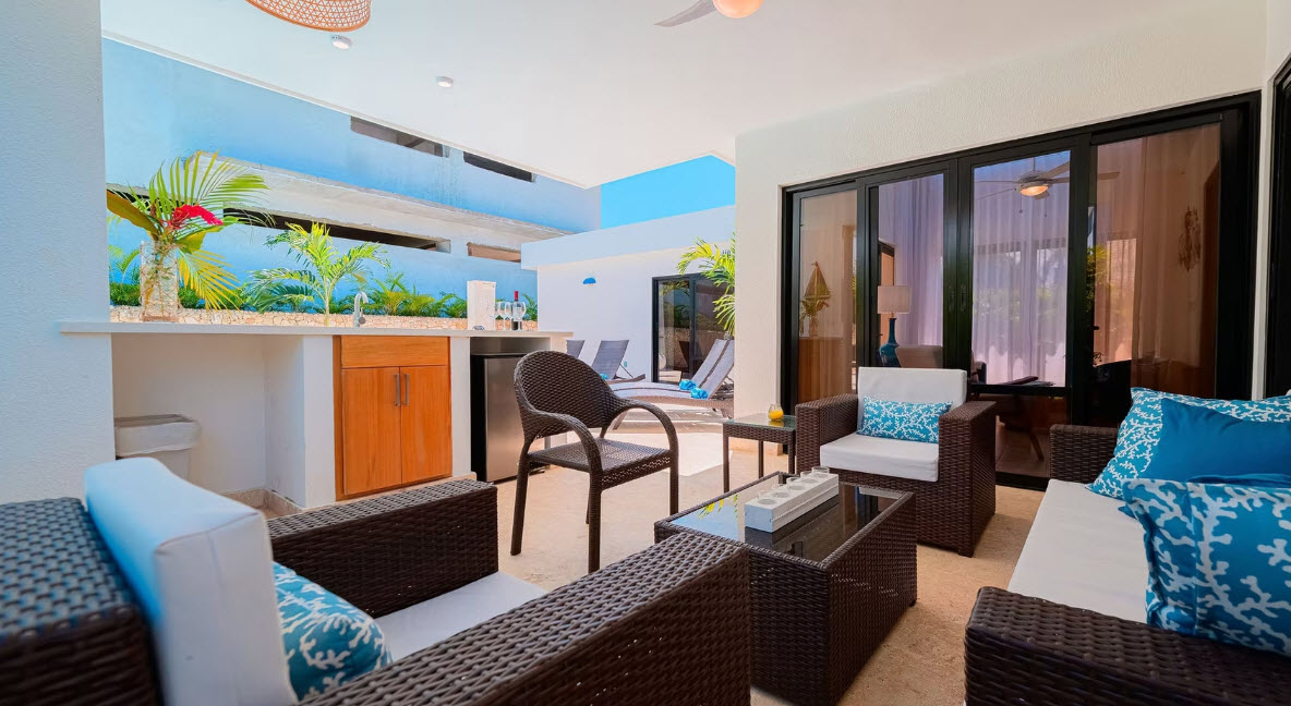 Modern outdoor patio with seating, mini-fridge, and pool view