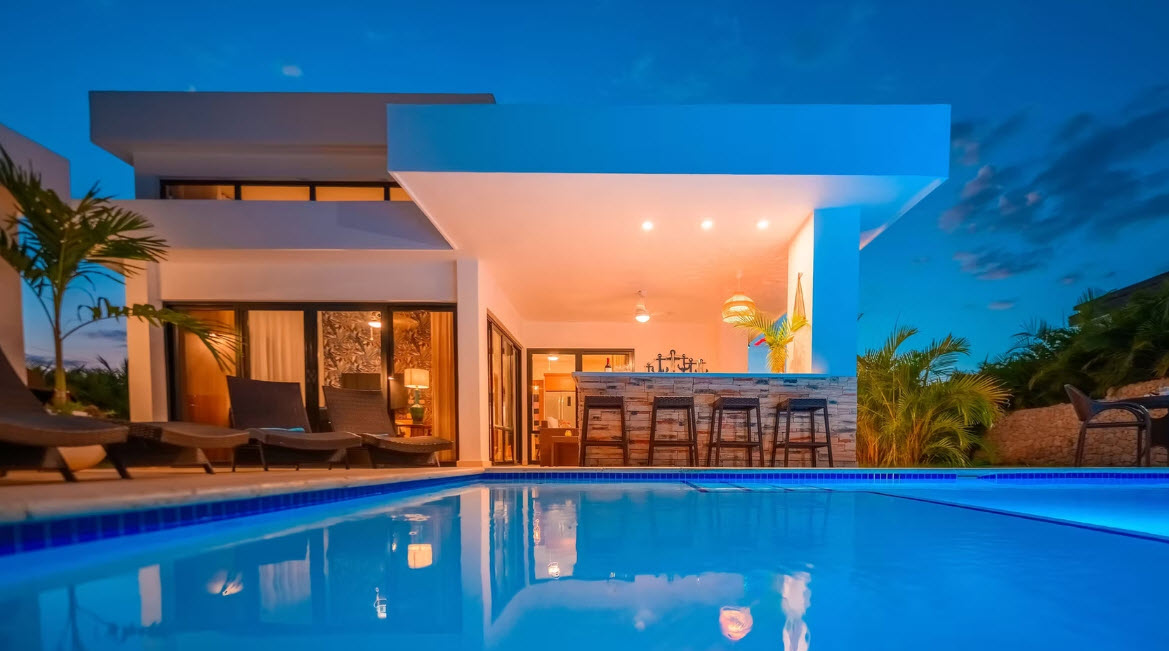 Modern villa with infinity pool and outdoor bar at dusk