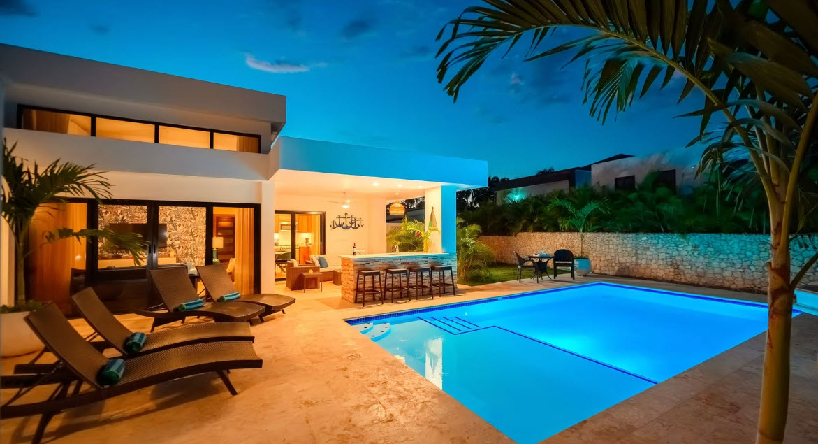 Luxury modern villa with illuminated pool and outdoor bar at dusk