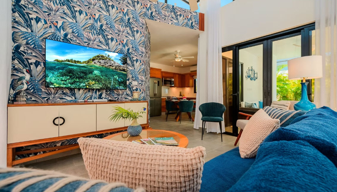 Modern living room with tropical wallpaper and ocean view on TV