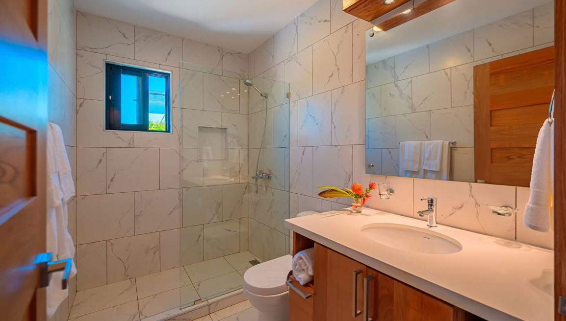 Modern bathroom with marble tiles, glass shower, and wooden vanity