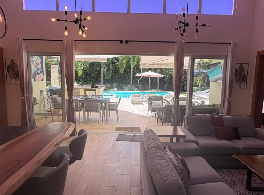 Modern living room with pool view, outdoor dining, and lounge area