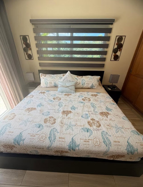 Coastal-themed bedroom with a queen-size bed featuring a seashell and coral print comforter.