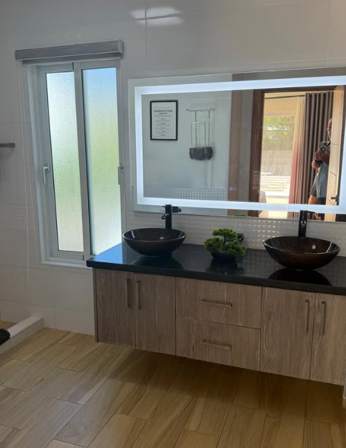 Modern bathroom vanity with double vessel sinks and illuminated mirror