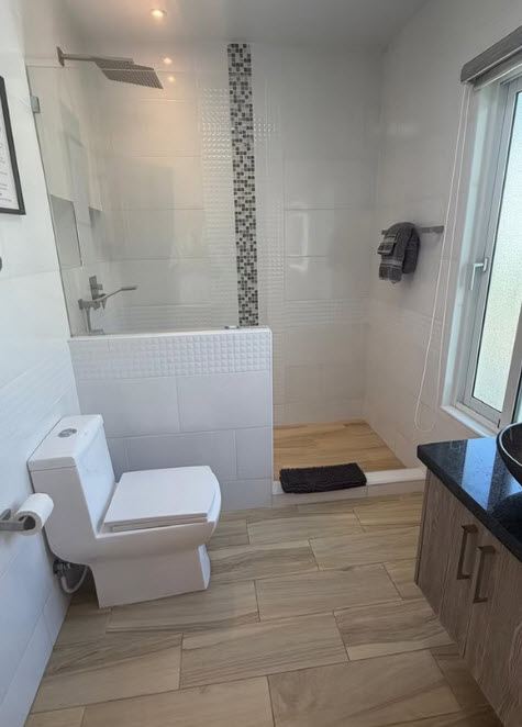 Modern bathroom with white tile, wood-look floor, and walk-in shower
