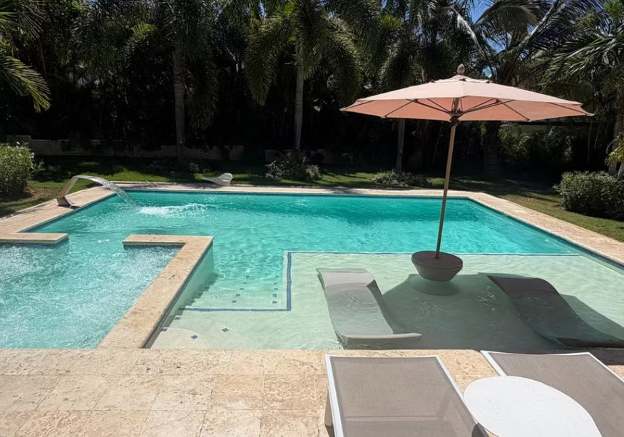 Luxury infinity pool with submerged loungers and waterfall feature