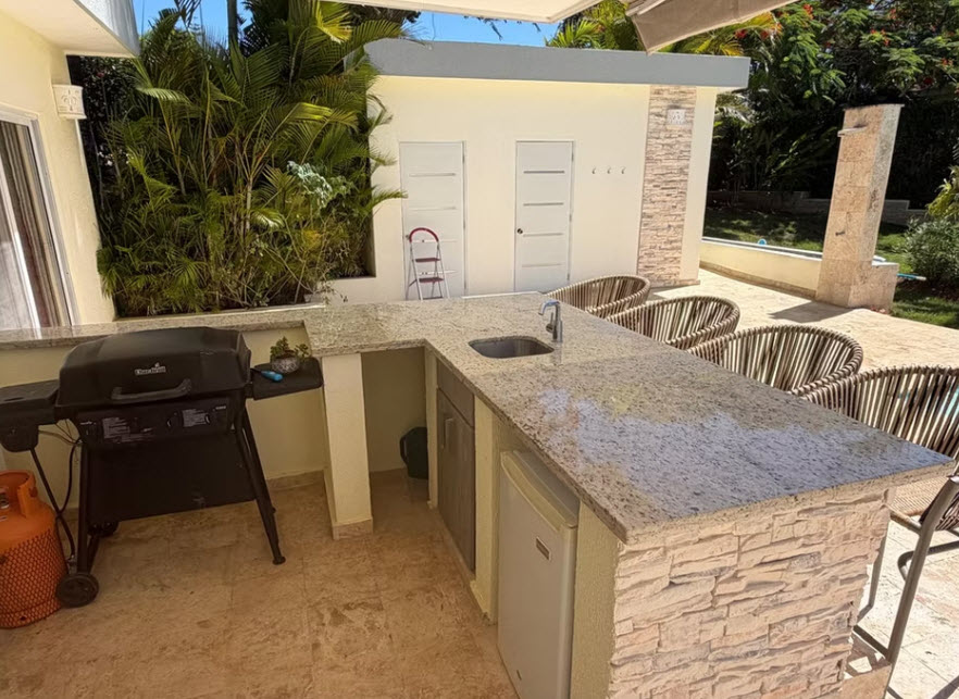 Outdoor kitchen with granite countertop, grill, sink, and bar seating