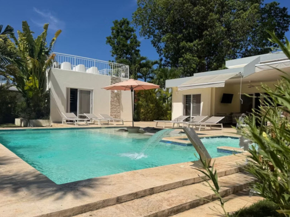 Luxury villa with swimming pool, sun loungers, and tropical garden.