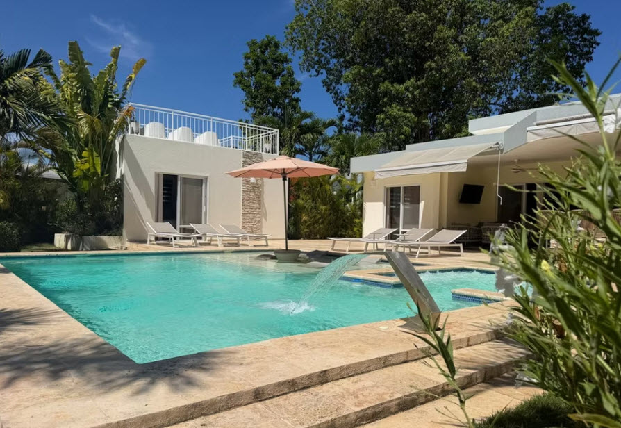 Luxury villa with swimming pool, sun loungers, and tropical garden.