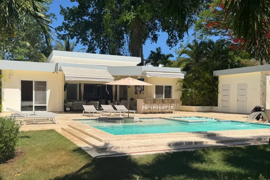 Modern villa with swimming pool, outdoor bar, and lounge chairs in a tropical setting.