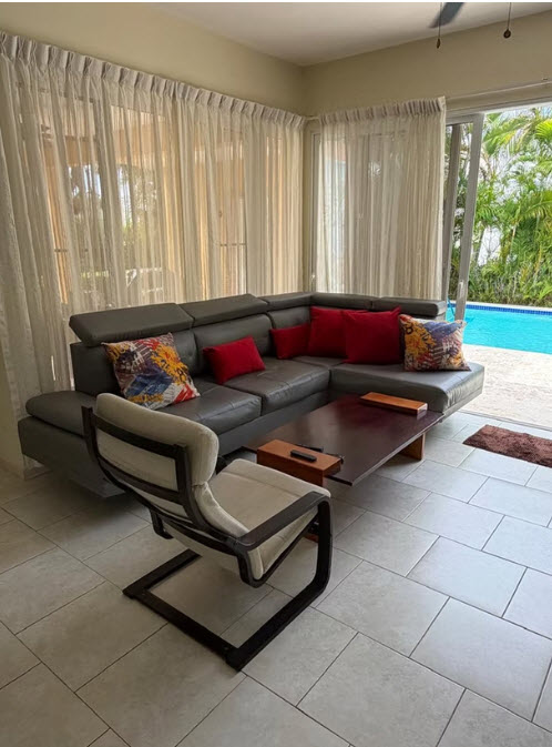 Modern gray sectional sofa with colorful pillows in a living room with a pool view