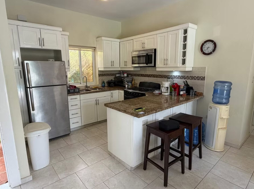 Modern white kitchen with stainless steel appliances and granite countertops.