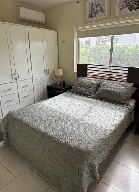 Cozy bedroom with a queen-size bed, large wardrobe, and window with natural light.