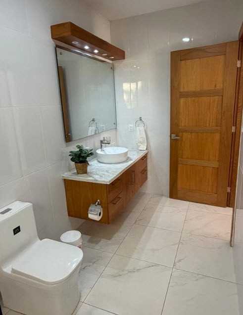 Modern bathroom with wood vanity, vessel sink, and toilet