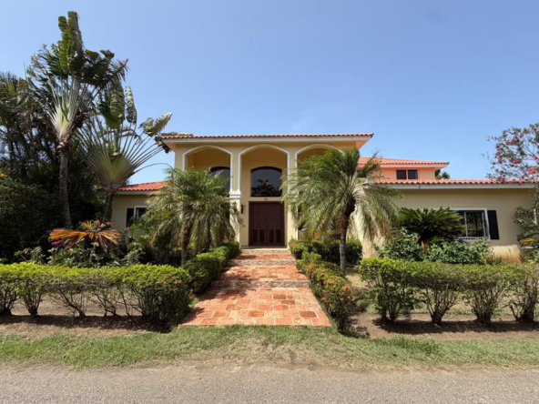 Luxury villa with palm trees and lush gardens under a clear blue sky.