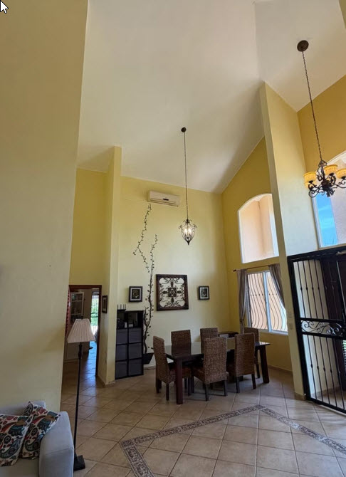 Spacious dining room with high ceilings, chandelier, and arched window