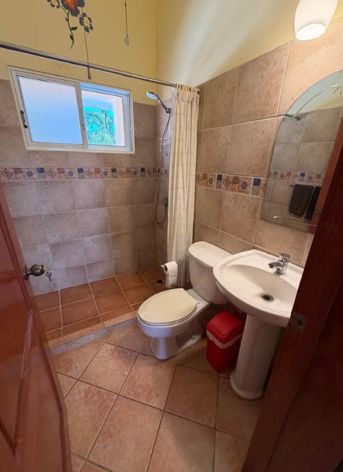 Small bathroom with tiled shower, toilet, sink, and mirror