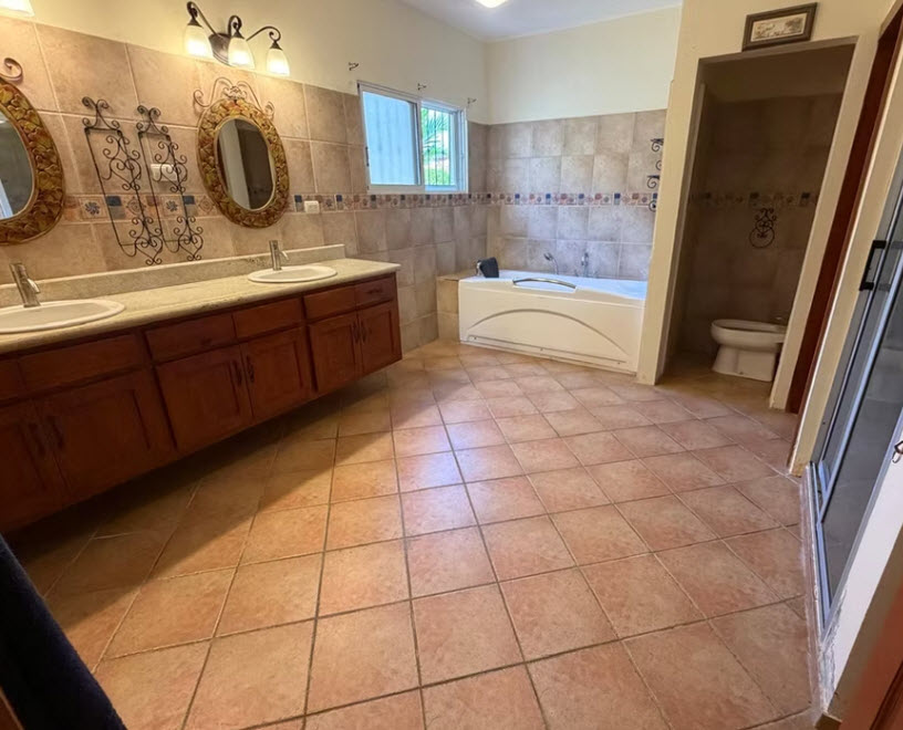 Spacious bathroom with double vanity, bathtub, and toilet