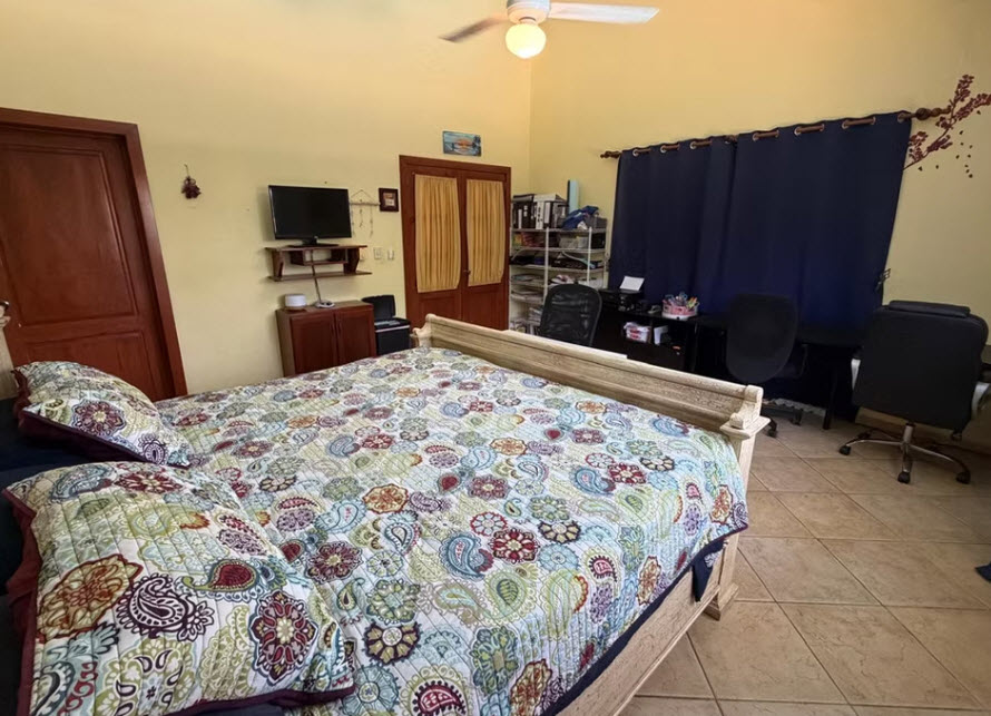 Colorful paisley comforter on a bed in a bright bedroom with desks.