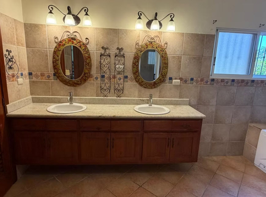Double vanity bathroom with two sinks, ornate mirrors, and wooden cabinets.