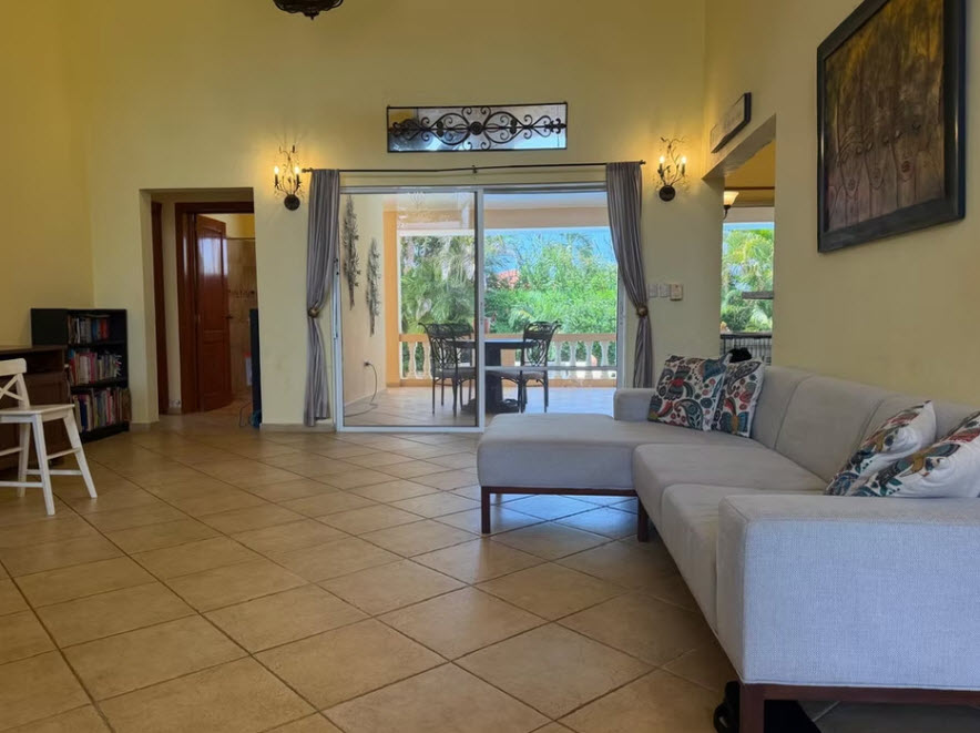 Spacious living room with a sectional sofa and view of a tropical patio