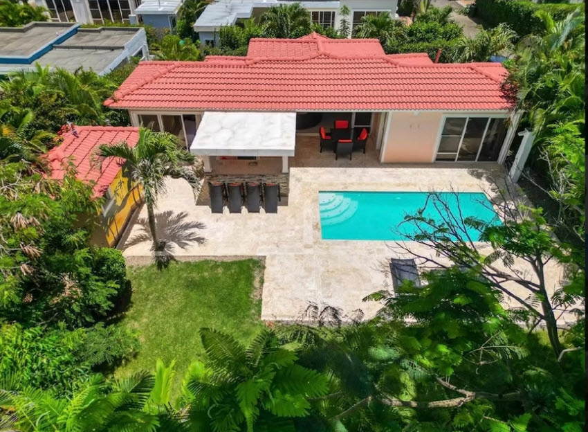 Luxury villa with red tile roof, swimming pool, and tropical landscaping