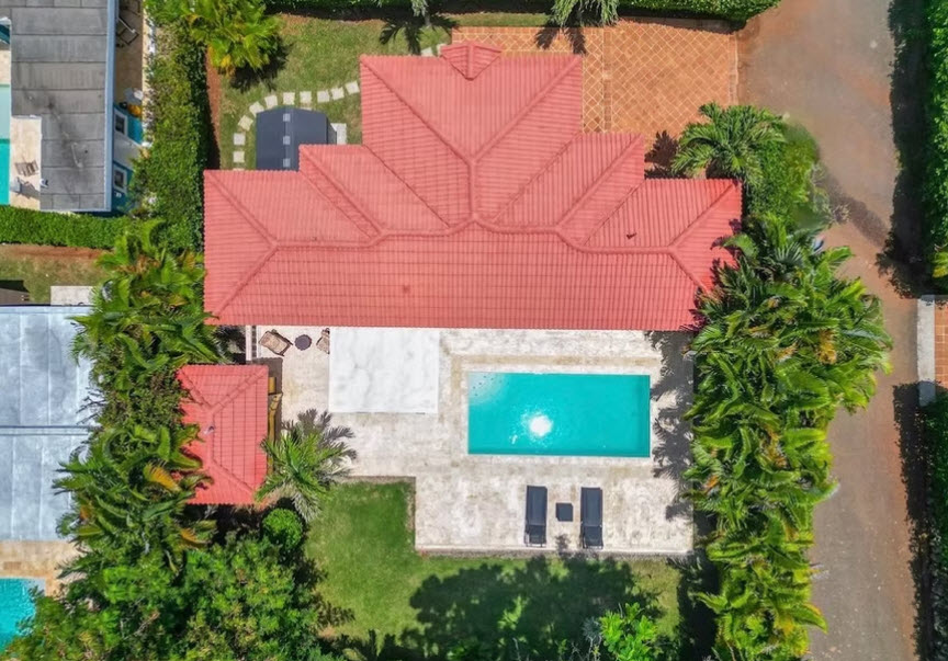 Aerial view of a luxury villa with a red-tiled roof, swimming pool, and lush greenery.